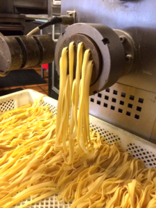 A machine is making pasta in the process of being made.