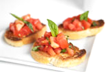 A plate of bruschetta with tomatoes and basil.