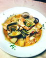 A bowl of seafood stew with parsley on the side.