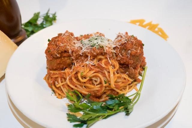 A plate of spaghetti and meatballs with parsley.